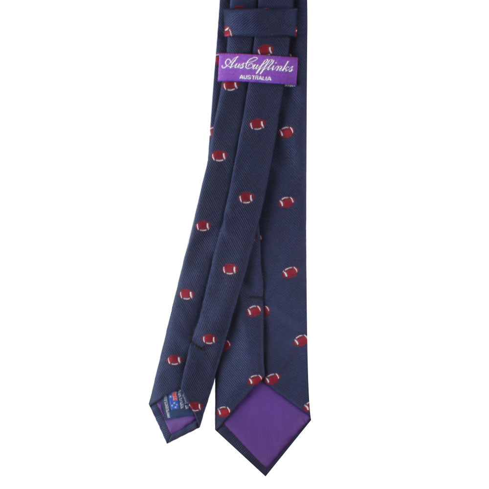 A navy blue Gridiron Fashion with small red football patterns, featuring a purple label with "Australia" text. The tie's lining is purple, adding a timeless charm to its athletic design.