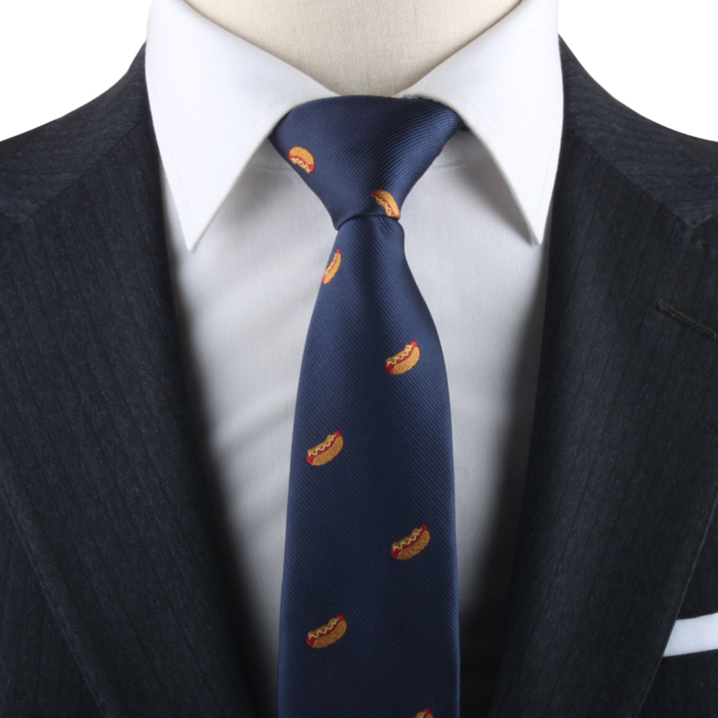 Close-up of a charismatic individual wearing a dark suit, white shirt, and the Hotdog Necktie featuring small orange logos.