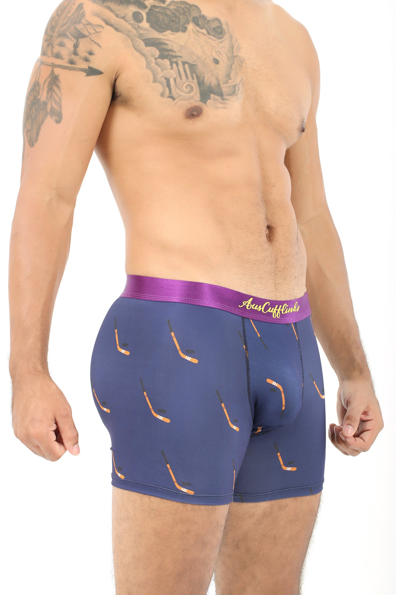 A man models the Ice Hockey Underwear, showcasing navy boxer briefs with a purple waistband and a hockey stick pattern, striking a relaxed pose against a white background.