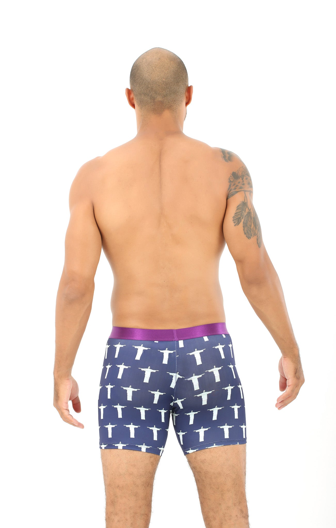 A person with a tattoo on their upper arm is standing with their back to the camera, wearing Jesus Underwear in navy blue with white cross patterns, providing a heavenly feel of comfort.