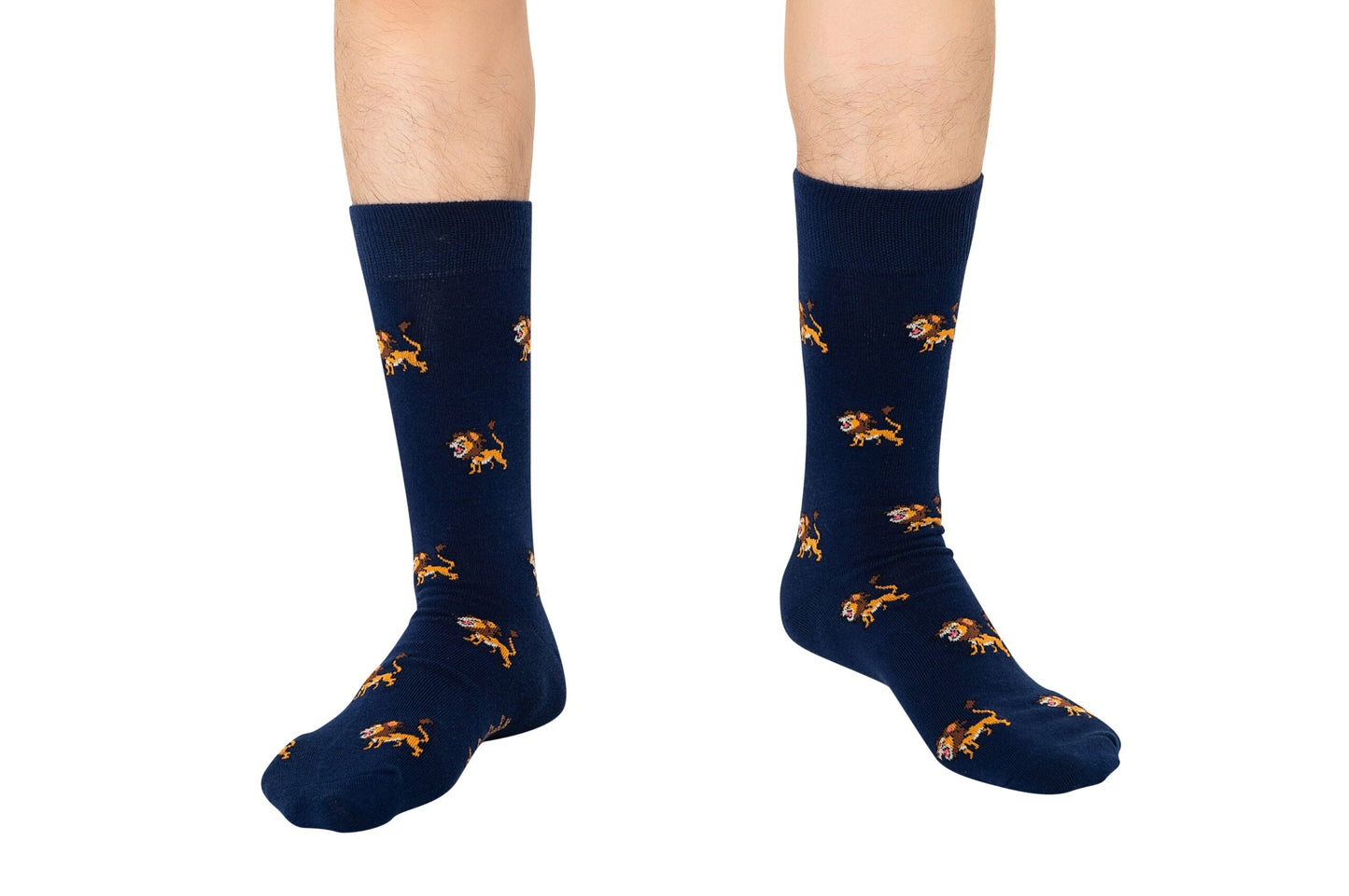 A person stands on a white background wearing Lion Socks, which are navy blue and decorated with small orange lion patterns.