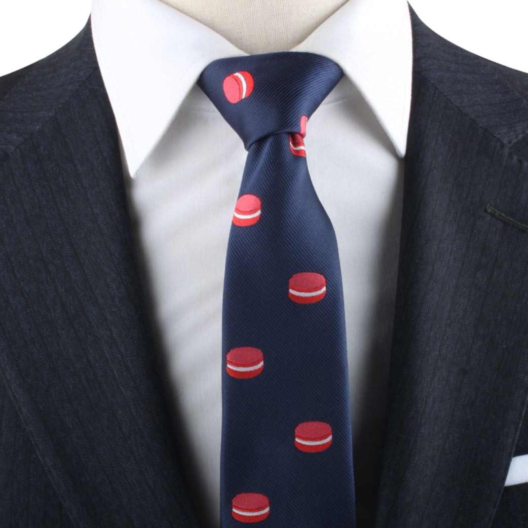 The Macaron Skinny Tie, featuring red macaron patterns, adds a playful flair for dessert enthusiasts when worn with a white shirt and dark suit.