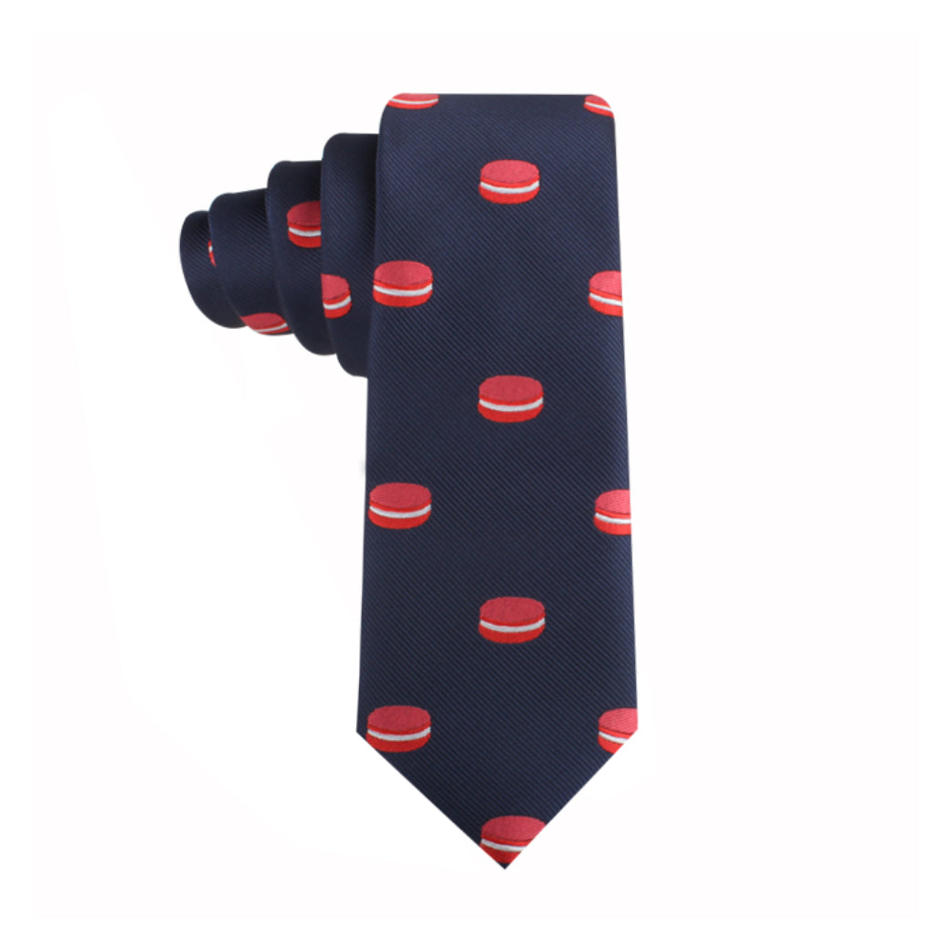 The Macaron Skinny Tie is navy blue and features a playful red and white hamburger pattern, reminiscent of gourmet desserts, neatly rolled on one side.