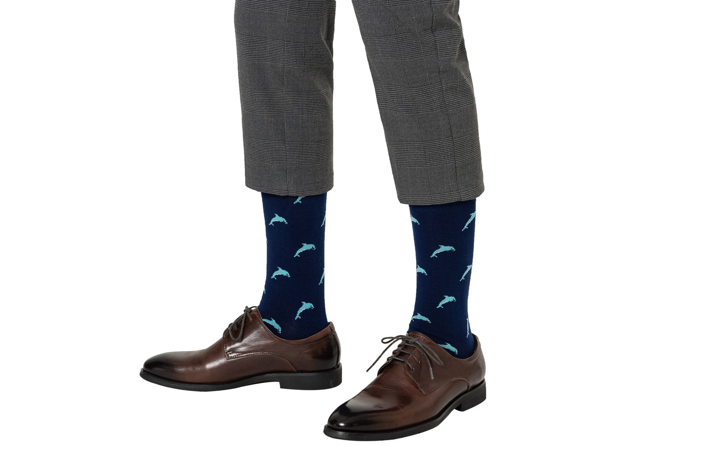 A person wearing gray plaid pants, brown dress shoes, and Dolphin Socks—navy blue ocean-themed novelty socks with light blue dolphin patterns.