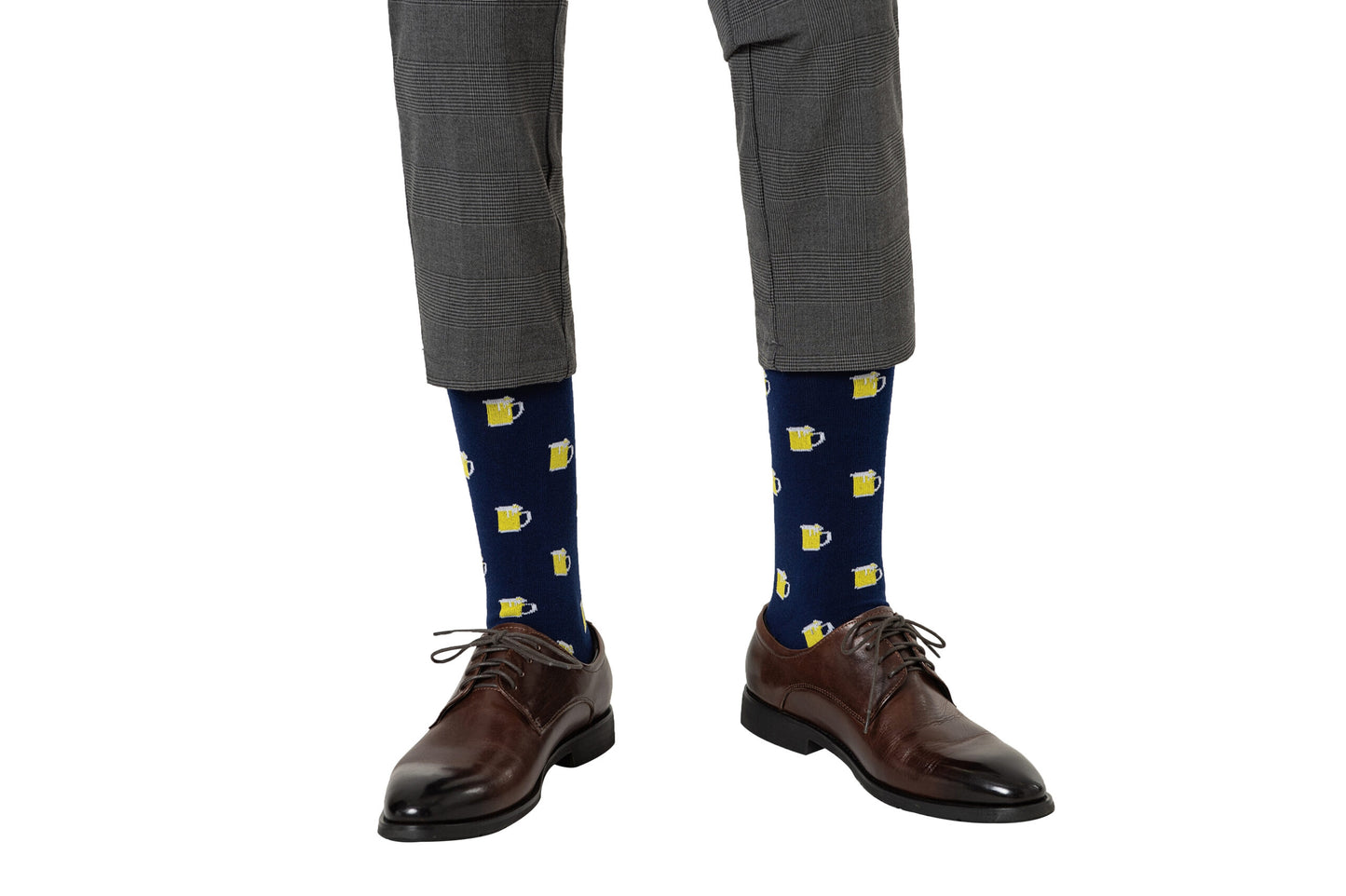 A person wearing gray plaid pants, brown dress shoes, and Beer Socks—navy blue socks with yellow beer mug patterns—perfect for beer lovers seeking a playful accessory.