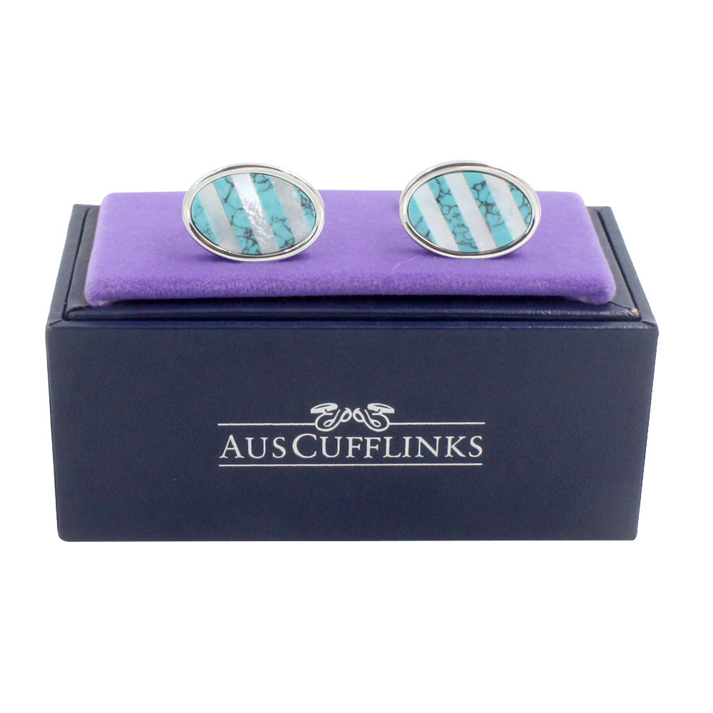 A pair of Turquoise Cufflinks – Bold & Elegant Style, featuring round silver design with blue and silver stripes, perfect for formal wear, displayed on a purple cushion atop a dark box labeled "AUSCUFFLINKS.