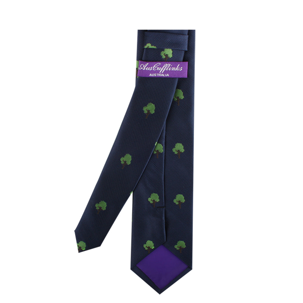 The Minimalist Nature Tie, featuring a navy base with green tree patterns, beautifully captures the essence of nature. A purple label and lining add a touch of fashion-forward flair.