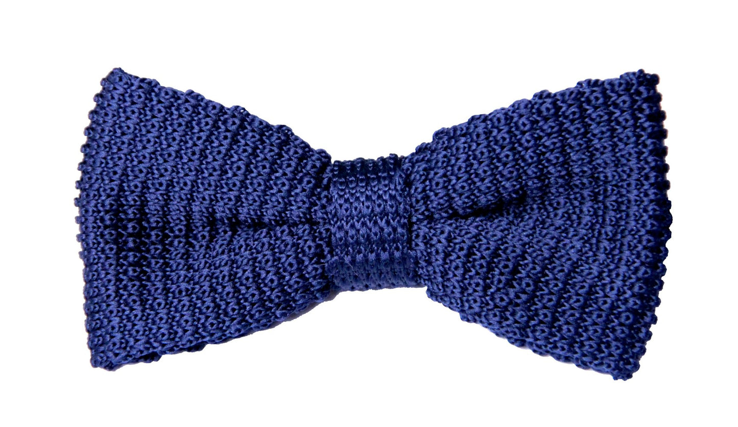 The Navy Knit Bow Tie is a sophisticated accessory featuring a textured woven pattern on a crisp white background.