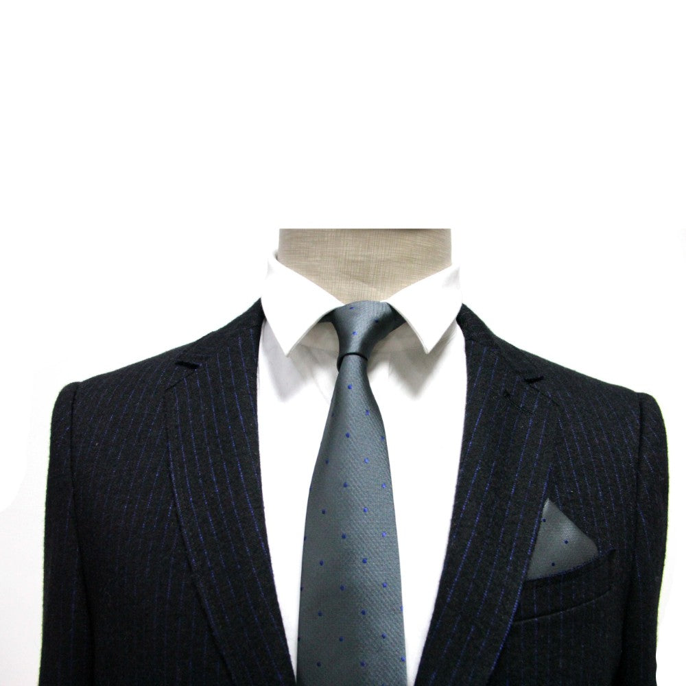A headless mannequin displays a dark pinstripe suit with a crisp white shirt and an elegant dotted tie. A Grey Navy Polka Dot Pocket Square peeks from the jacket, showcasing men's fashion accessories at their finest.