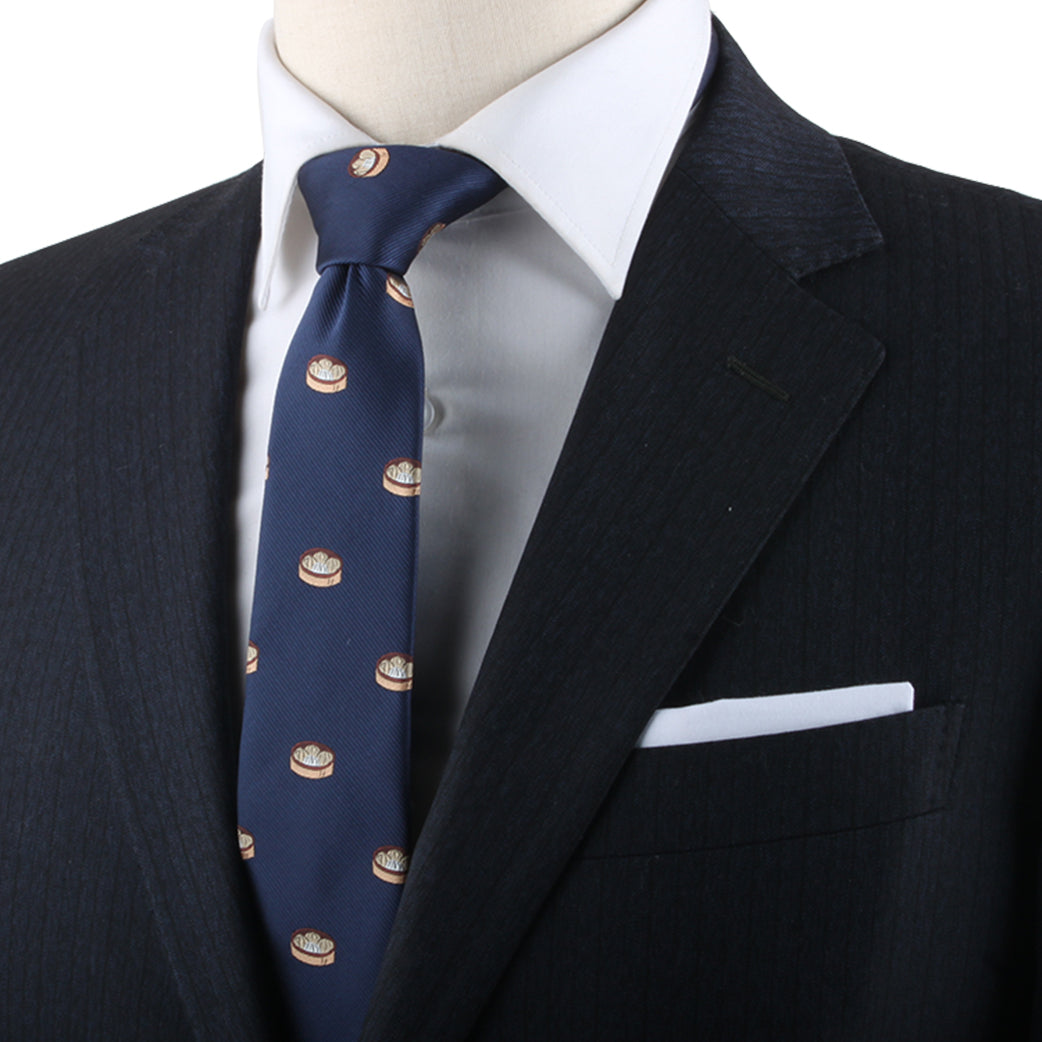 A person in a dark suit with a white dress shirt and a Dumplings Skinny Tie featuring a circular pattern exudes timeless elegance.