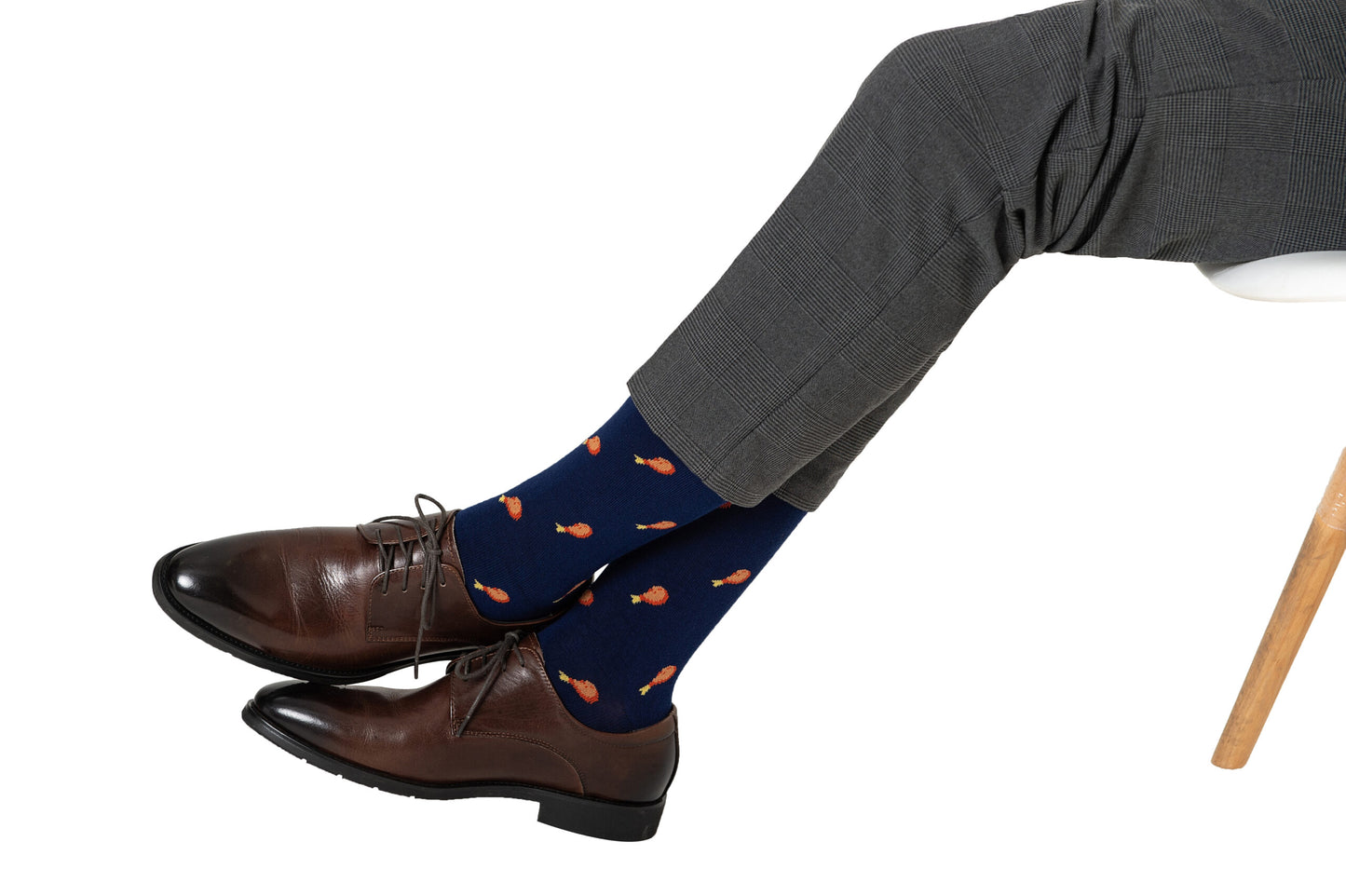 Dressed in a layered style, this person sports gray checkered pants, Strawberry Cake Socks with orange patterns, and brown leather shoes, all set against a white background.