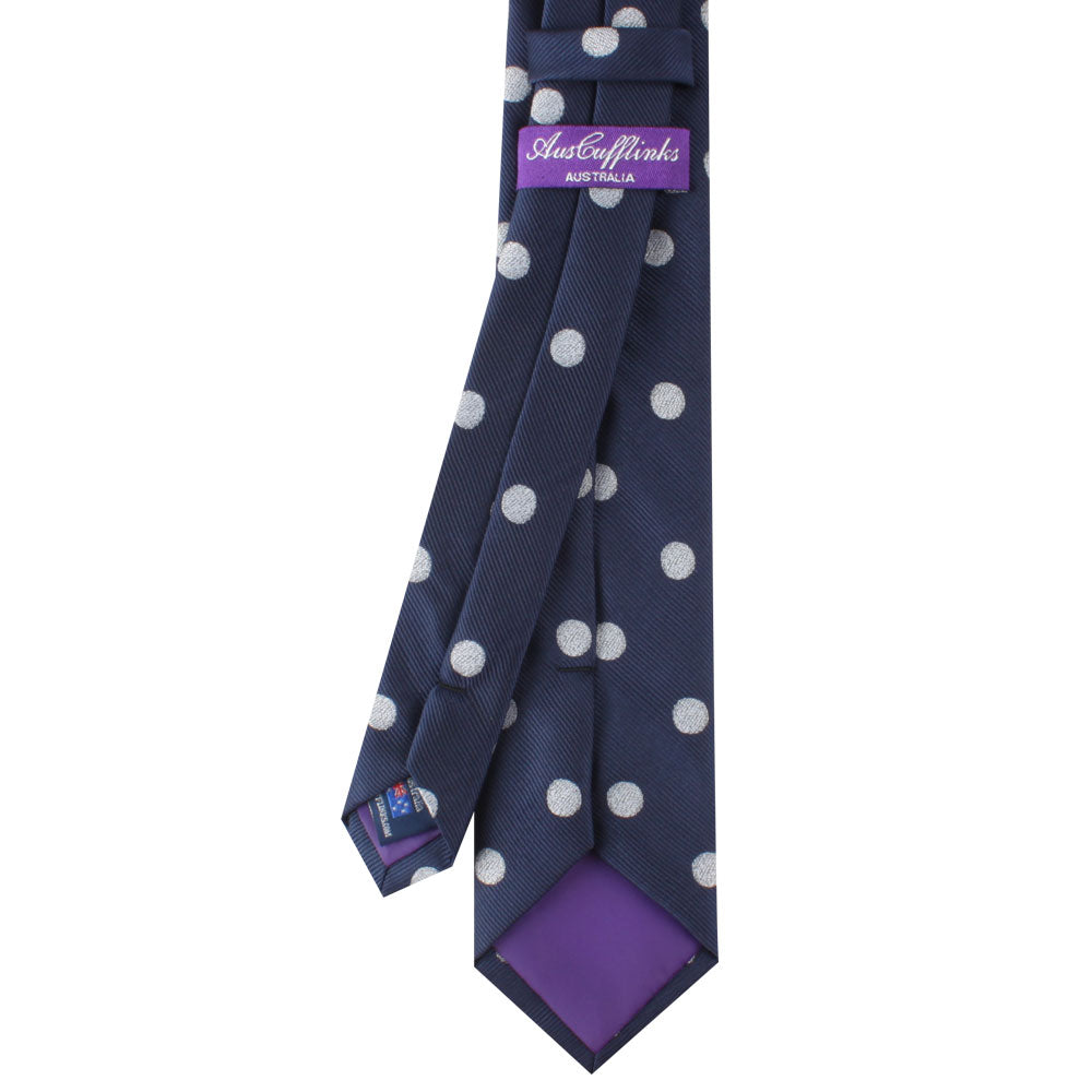 The Novelty Golf Tie, featuring a navy blue design with white polka dots and a purple lining, is perfect for golf enthusiasts. It comes with tags labeled "Aust & Finks" and "Made in Australia.