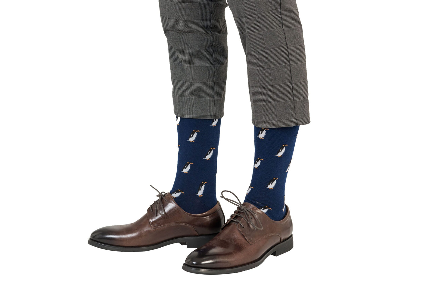 A person wearing gray plaid pants, Penguin Socks that exude arctic allure, and brown leather dress shoes.