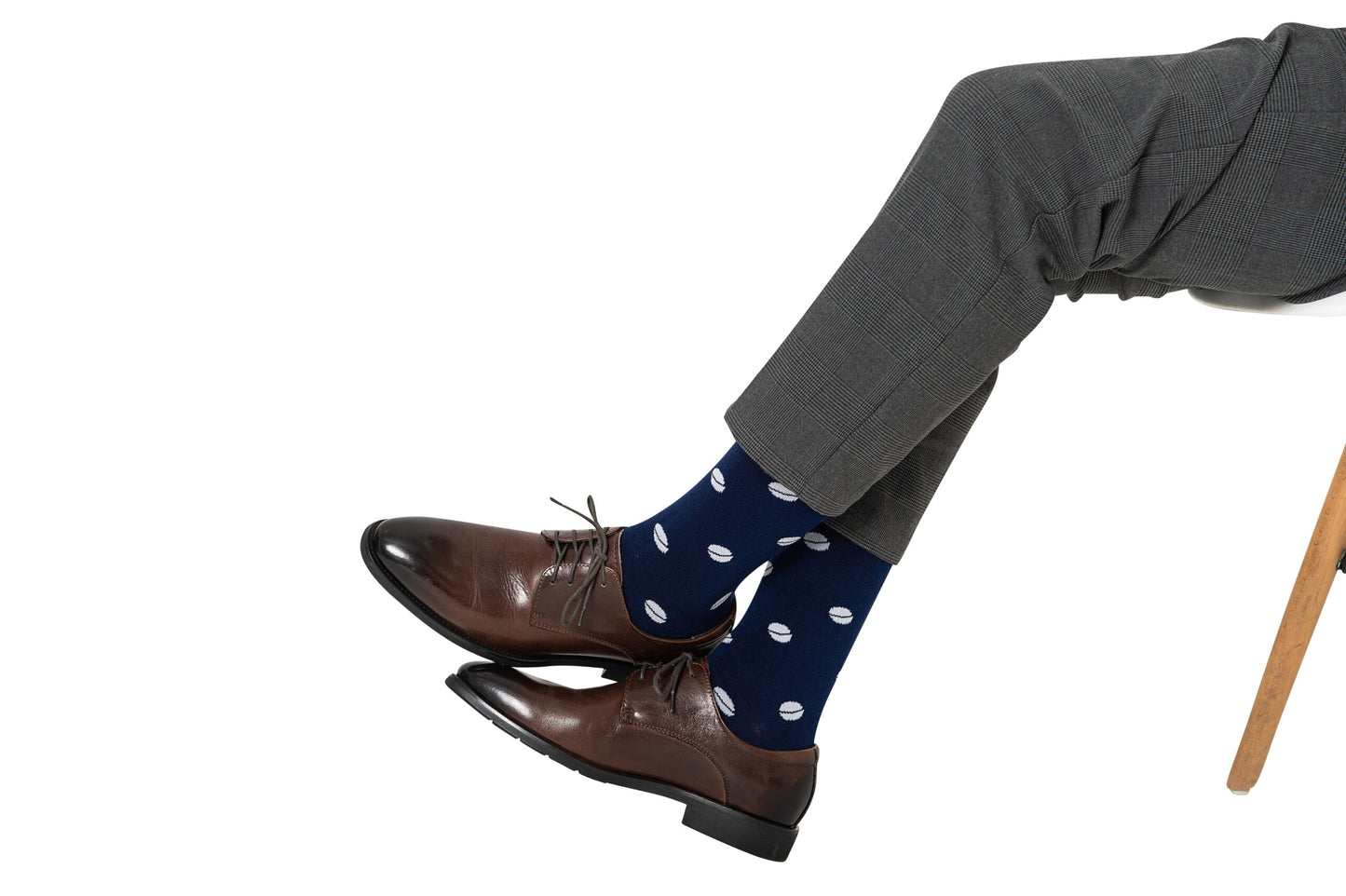Man in gray pants and Rugby Socks with brown leather shoes crossed over on a white background, ready to tackle the day.