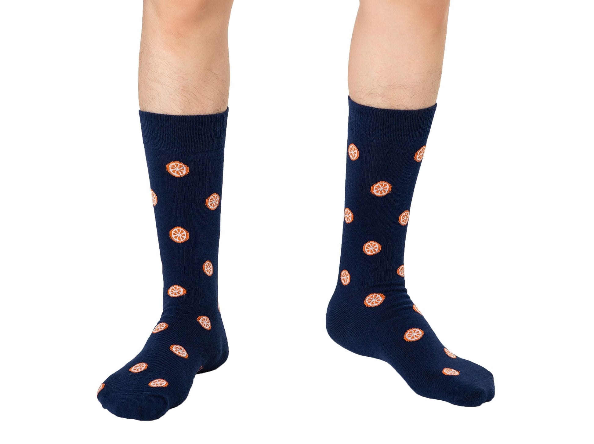 A pair of legs enveloped in Orange Socks, featuring orange circular patterns and extending from heel to toe, is isolated against a pristine white background, offering a visual testament to citrusy comfort.
