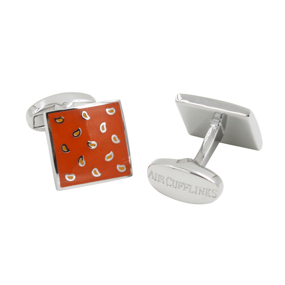 A pair of Tear Drop Orange Cufflinks with square, orange faces adorned with a pattern of small, white and black paisley designs. The rear side of one cufflink is engraved with text. These accessories add a splash of zest to any formal attire.