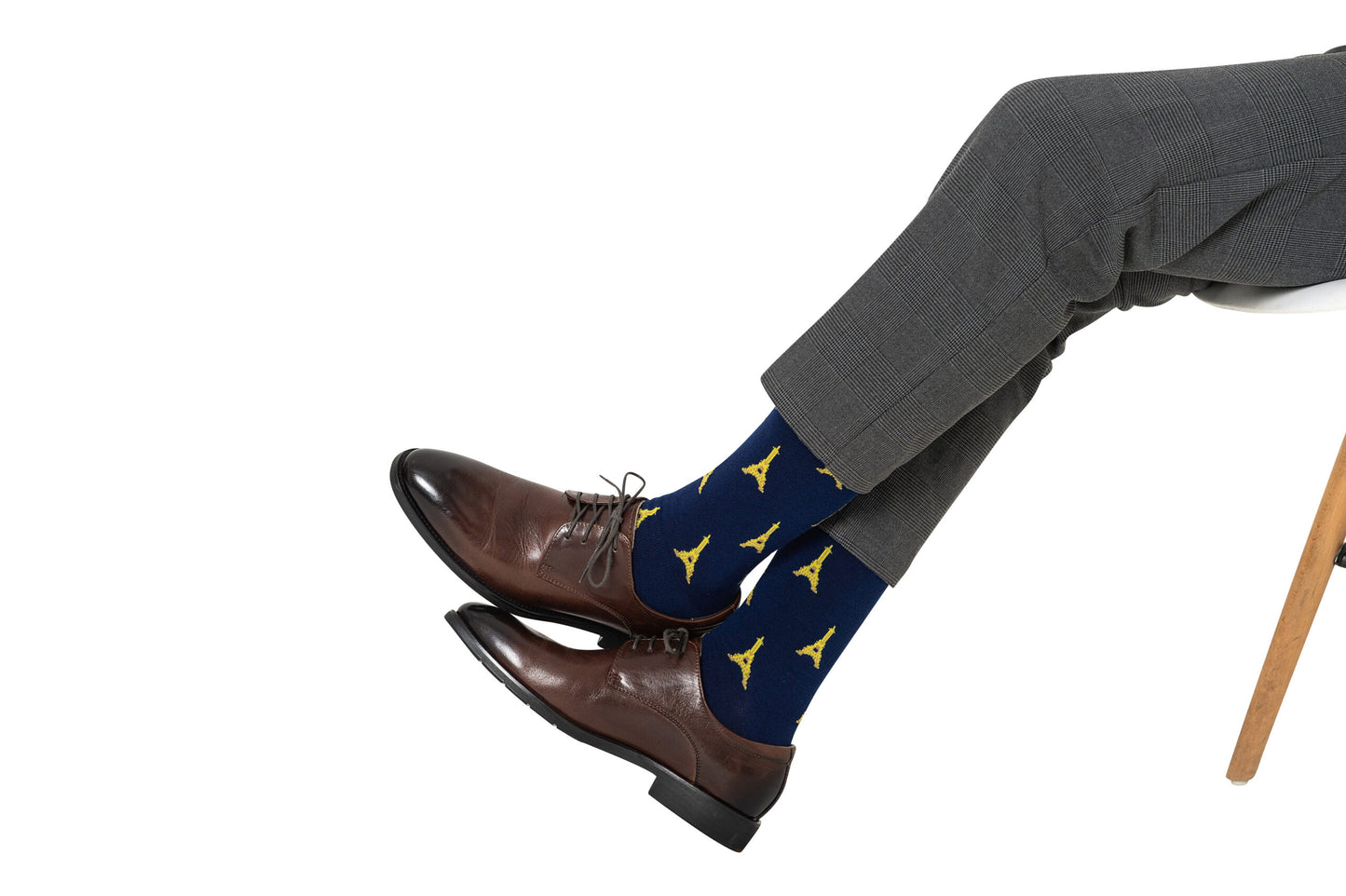 A man sitting on a chair wearing a pair of Eiffel Tower socks.