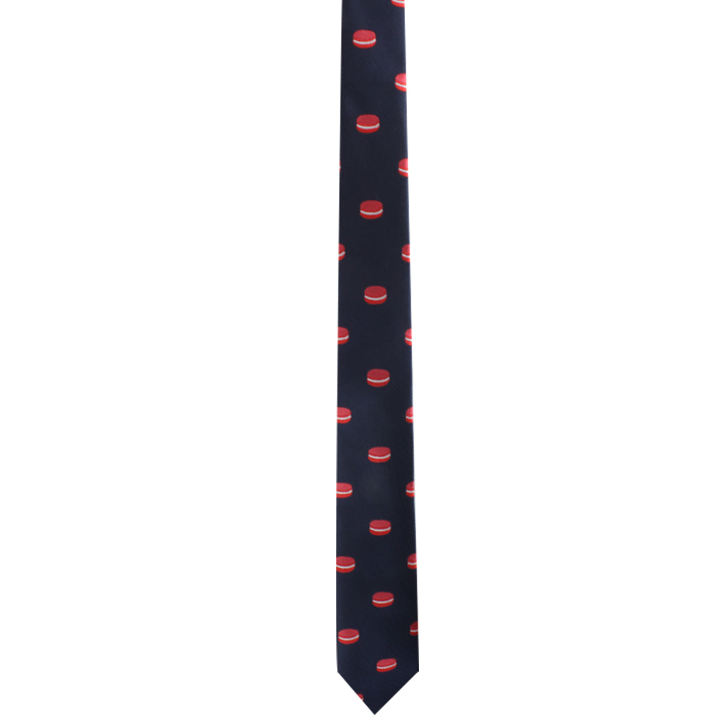 The Macaron Skinny Tie in navy blue, adorned with a delightful pattern of small red hockey pucks, is ideal for dessert lovers who seek a blend of playful and sophisticated style.