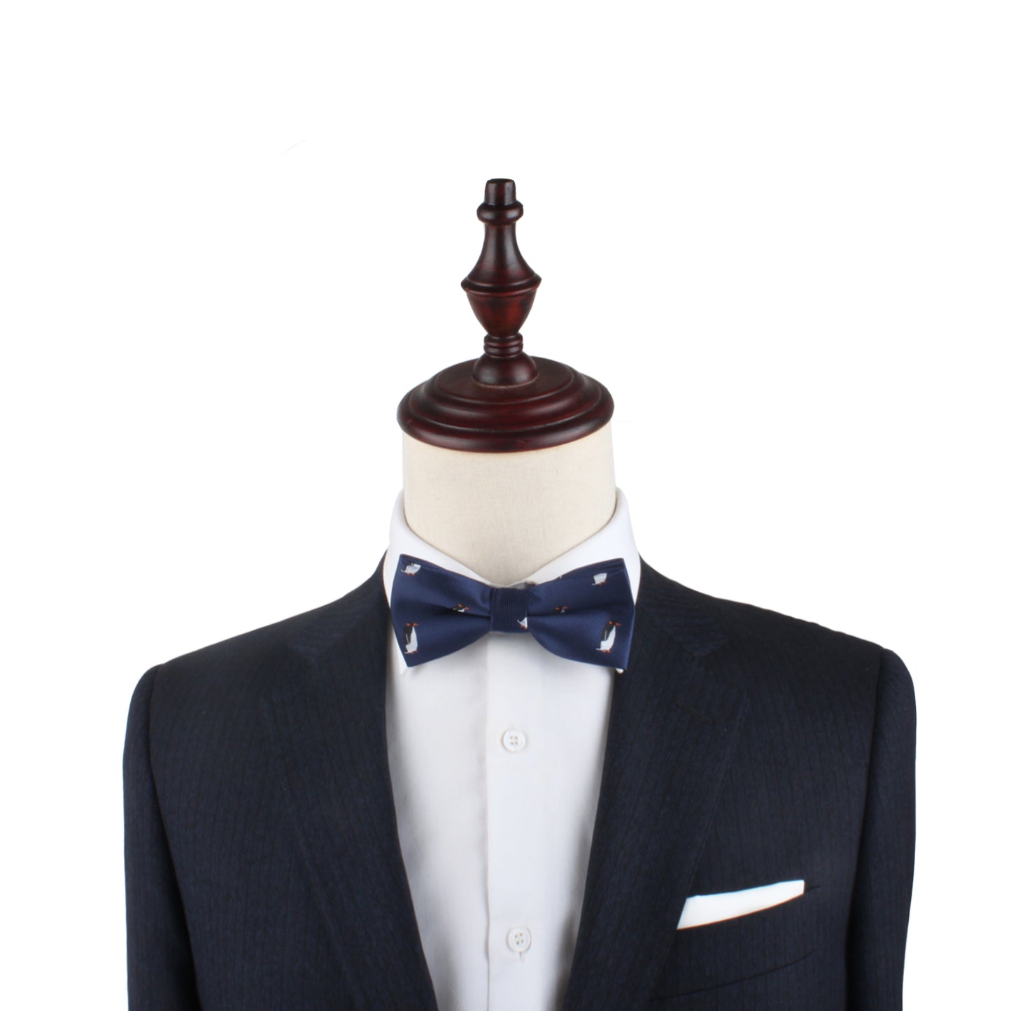 A mannequin dressed in a dark suit, white dress shirt, **Penguin Bow Tie**, and a white pocket square exudes cold elegance on a plain white background.