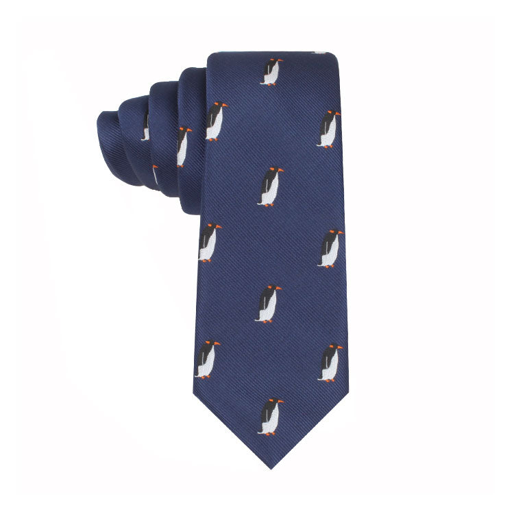 A neatly rolled Penguin Necktie featuring a pattern of small penguins with orange beaks and feet, blending timeless elegance with whimsical charm.