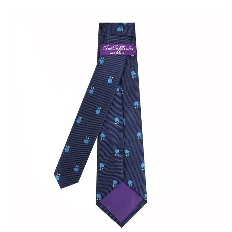A dark blue tie with a pattern of small blue teardrop shapes and a purple label displaying the brand name "Pickle Ball Skinny Tie" radiates refined charm. The inner lining is purple, adding an extra touch of sophistication.