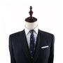 A dark blue pinstripe suit, white dress shirt, Pineapple Slim Tie, and a white pocket square displayed on a mannequin with a wooden top exude modern elegance.