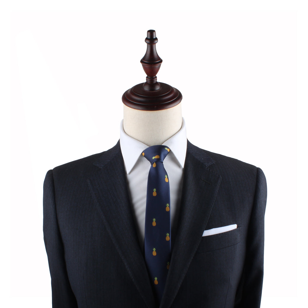 A dark blue pinstripe suit, white dress shirt, Pineapple Slim Tie, and a white pocket square displayed on a mannequin with a wooden top exude modern elegance.