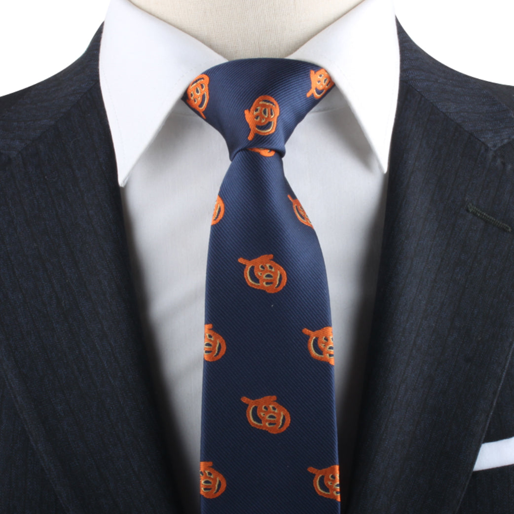 A person in a dark suit and white shirt exudes charisma, wearing the Pretzel Necktie adorned with an orange pumpkin pattern.