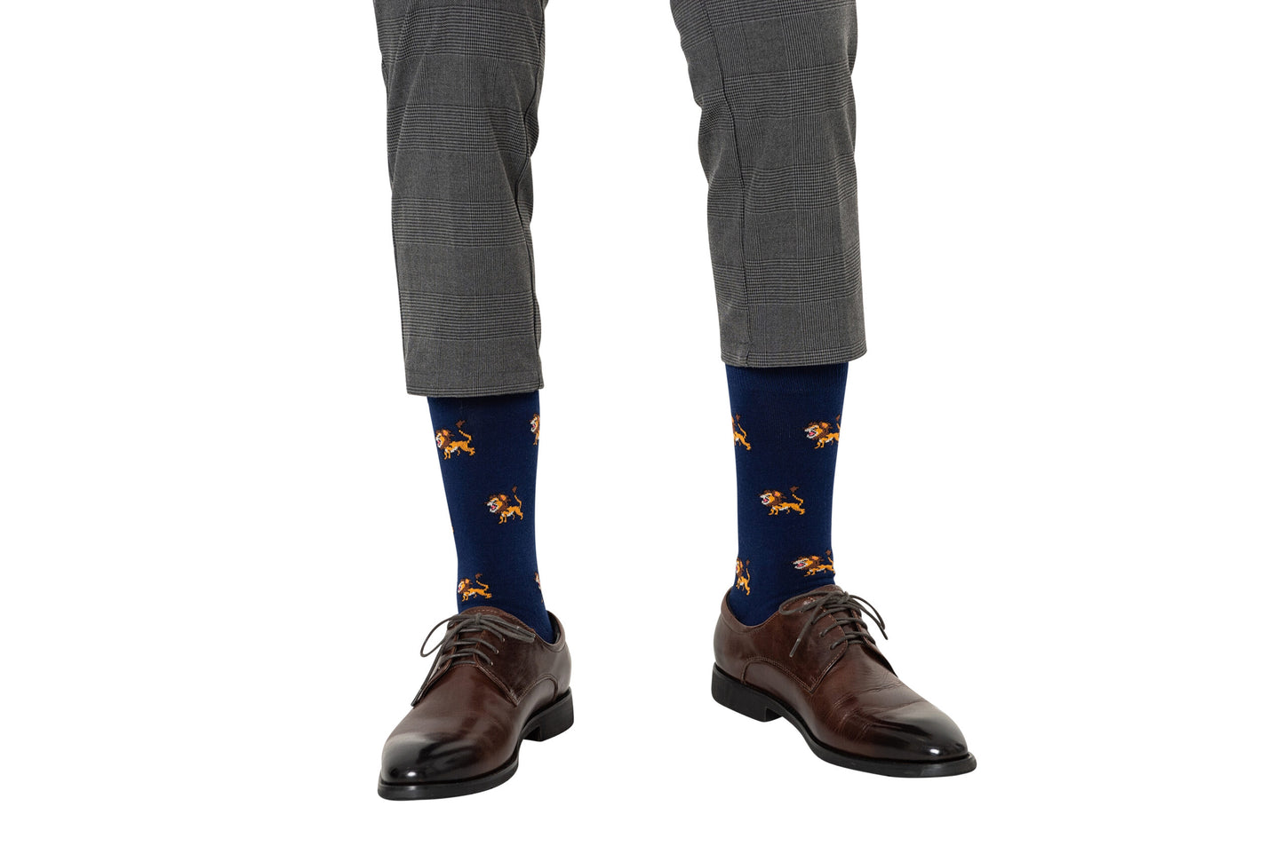 A person wearing Lion Socks—blue socks with an orange lion print—paired with gray checkered trousers and brown dress shoes, standing on a white background.