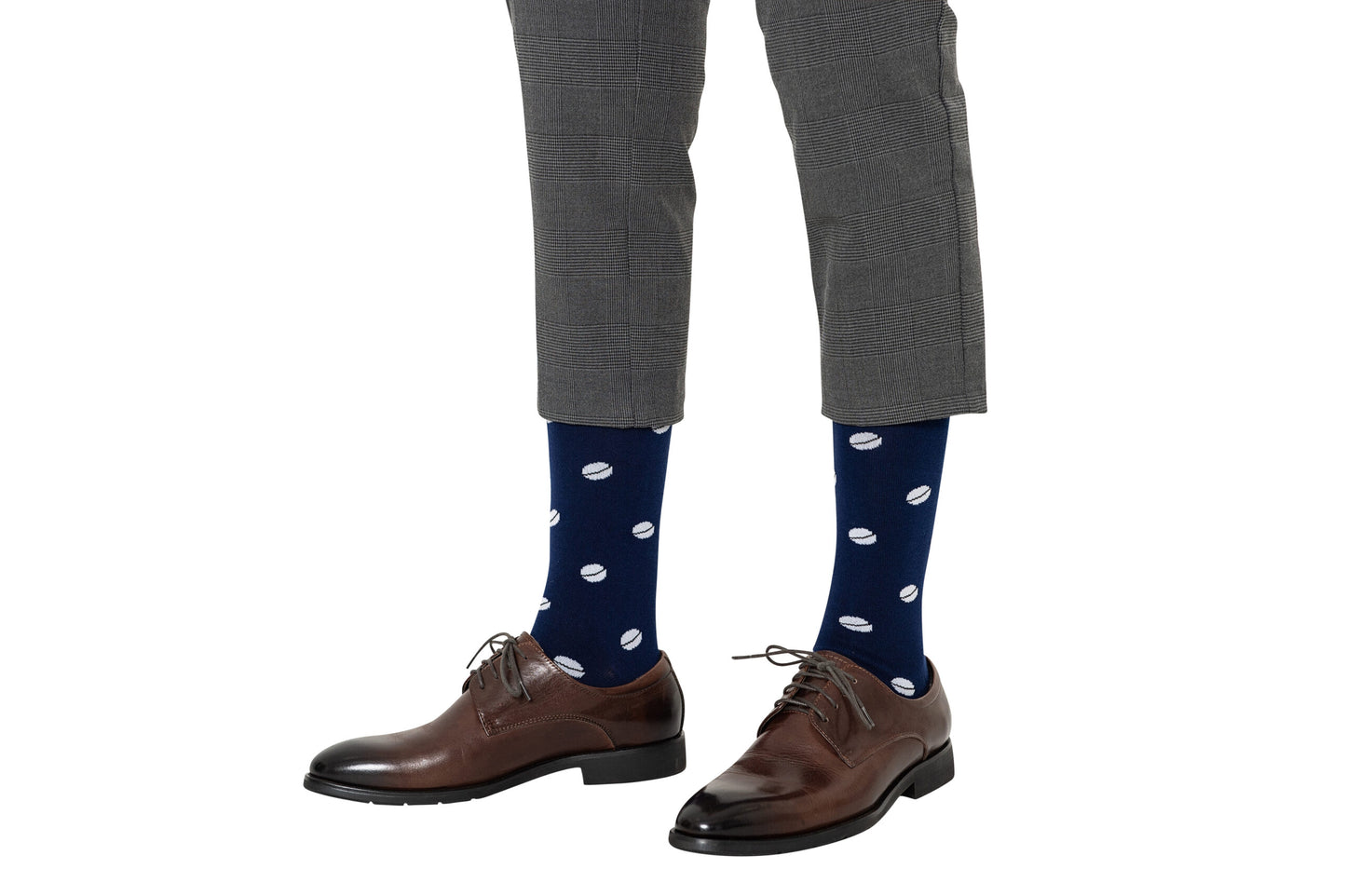 Close-up of a person’s lower legs wearing gray plaid trousers, Rugby Socks with white polka dots, and brown lace-up shoes, ready to tackle the day.