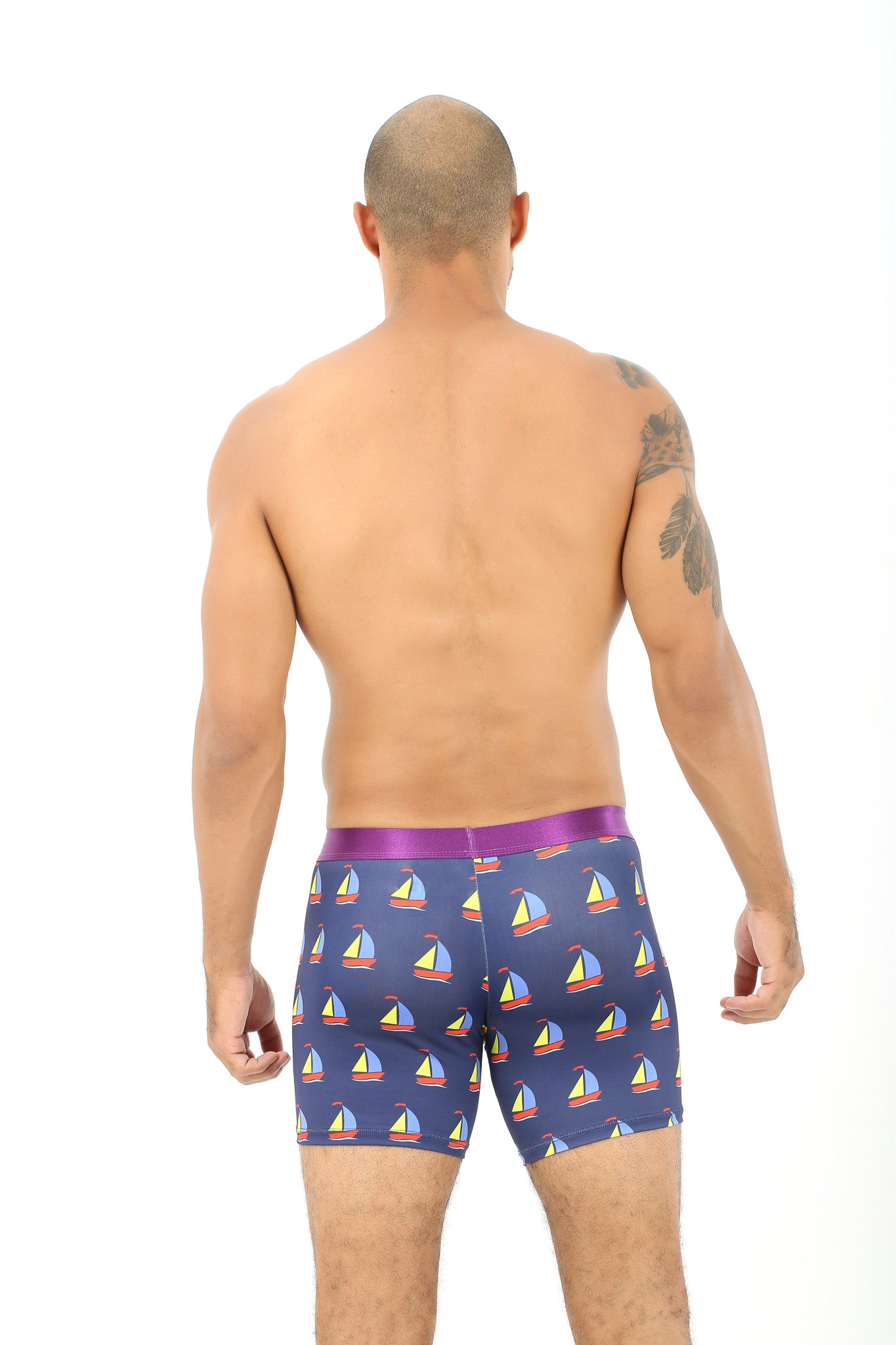 A man, facing away from the camera, is wearing the Sail Boat Underwear in blue, featuring a comforting sailboat design that evokes images of gentle waves.