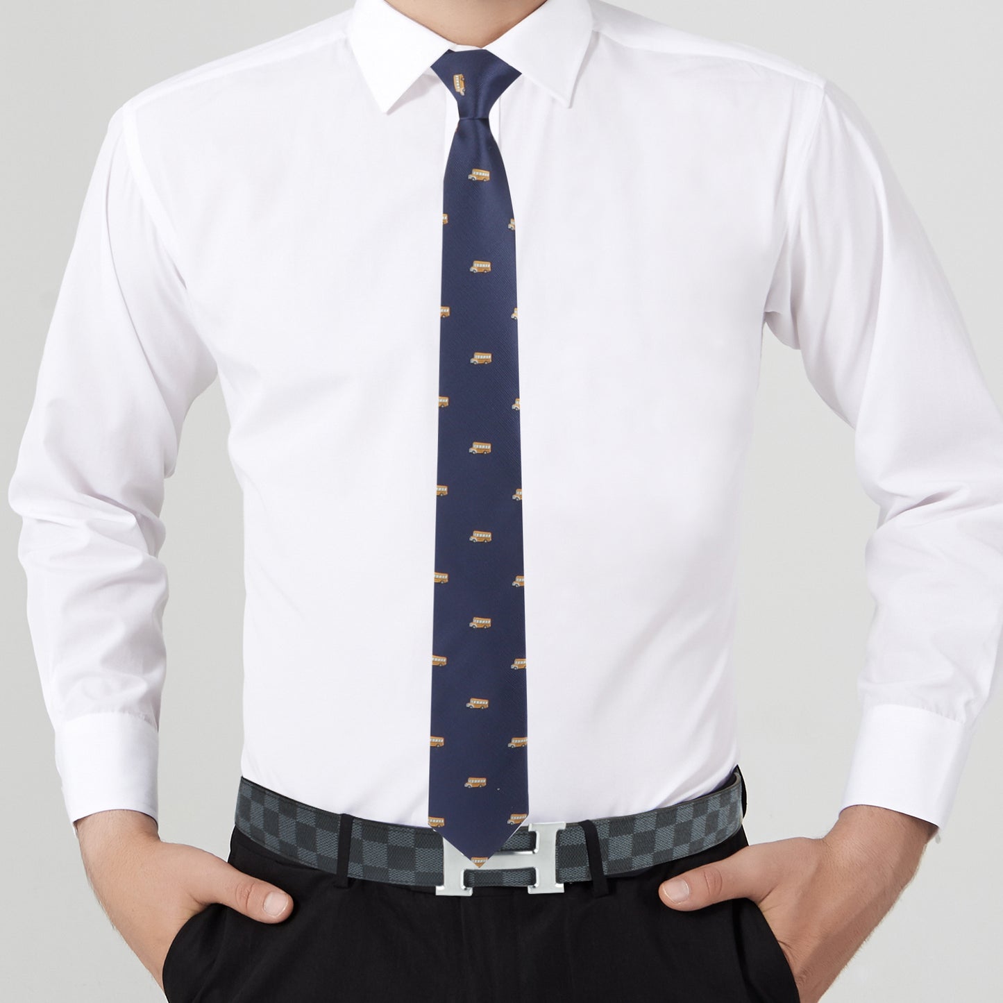 Close-up of a man in a white shirt and School Bus Driver Tie, hands on hips with a grey checkered belt visible.
