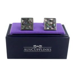 A pair of Signature Malachite Cufflinks with a stellar mosaic design, presented on a purple cushion inside an "auscufflinks" branded box.