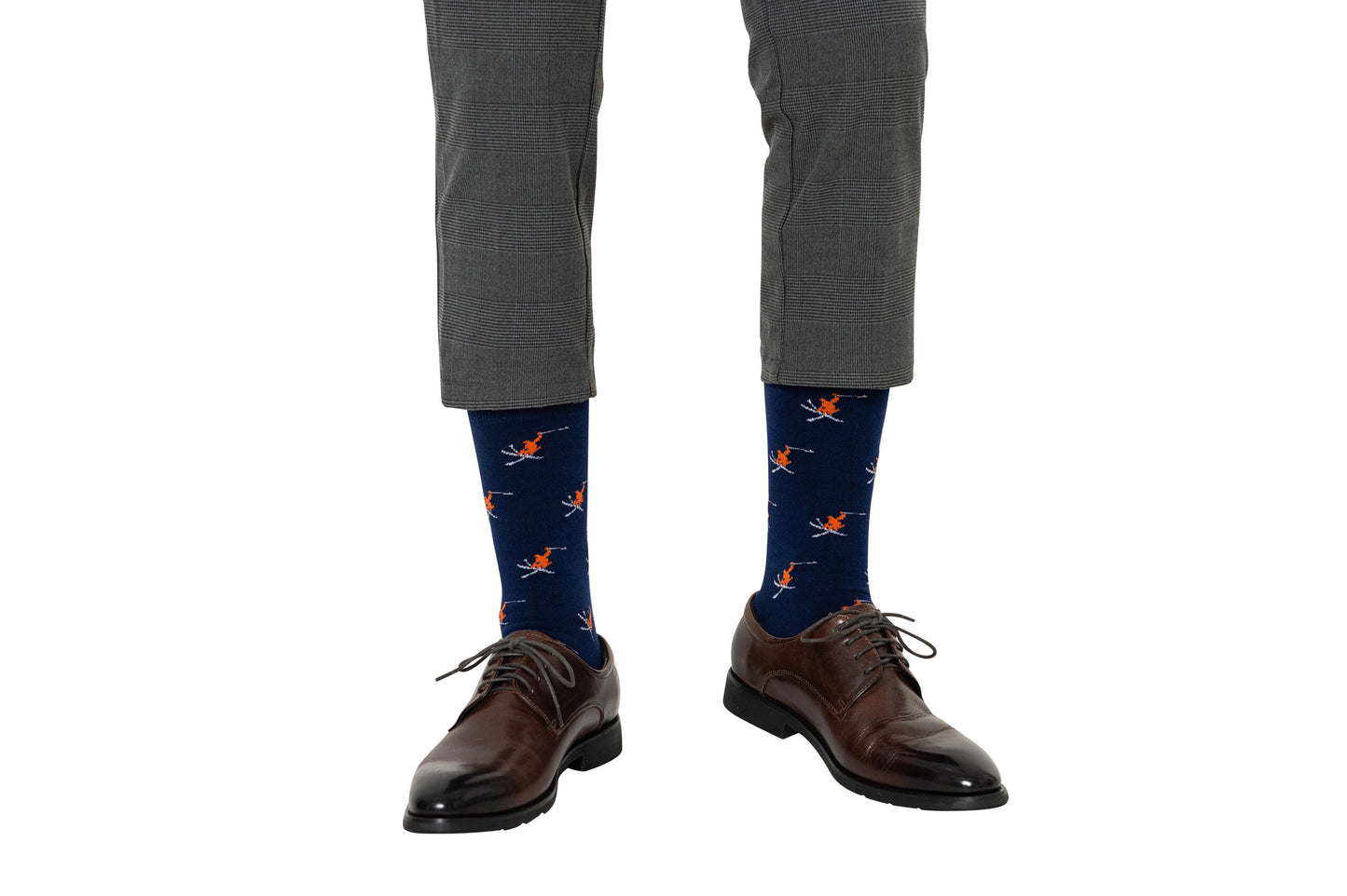 A person wearing gray plaid pants, Ski Socks in blue with a pattern, and brown dress shoes, standing on a white background.
