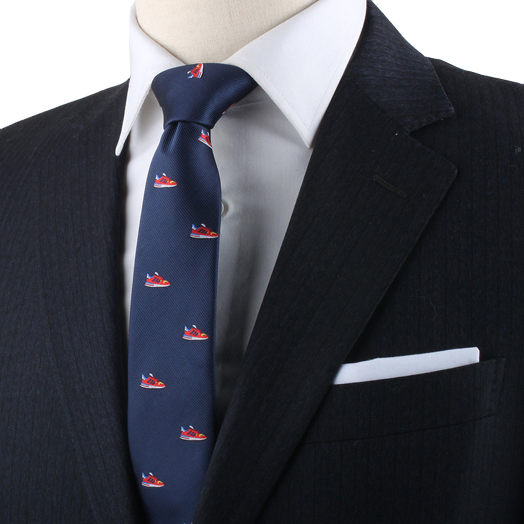 Close-up of a person wearing a dark suit jacket with a white dress shirt and a Sneaker Lover Gift. The jacket, accented with a white pocket square, exudes modern style and urban flair.