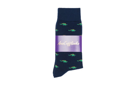 A single navy blue Stegosaurus sock with an alligator pattern and a whimsical purple band featuring the text "just lilies.