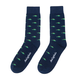 A pair of Stegosaurus socks featuring a whimsical green crocodile pattern and brand logo text on a white background, all adding a touch of prehistoric charm.