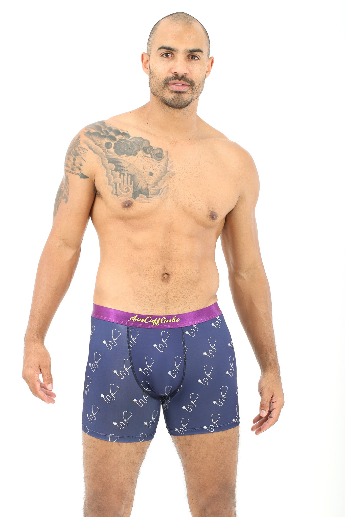 A man with a tattoo on his shoulder is posing in Stethoscope Underwear, exuding an aura of coziness.