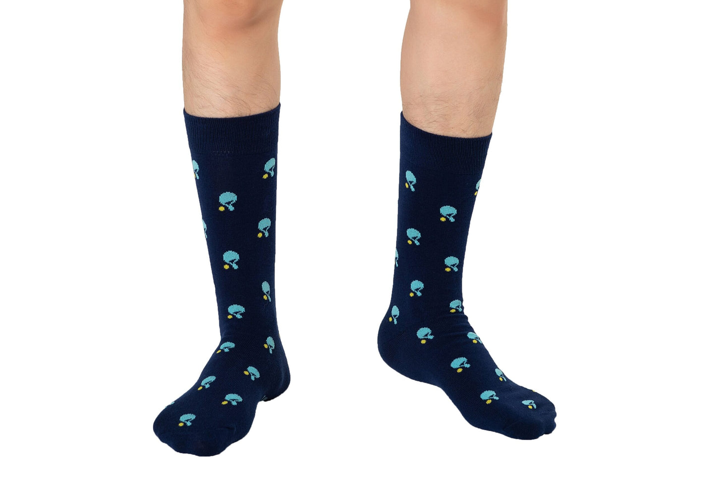 A person stands on a white background wearing navy blue Table Tennis Socks, featuring a pattern of small blue mushrooms and crafted from breathable fabric.