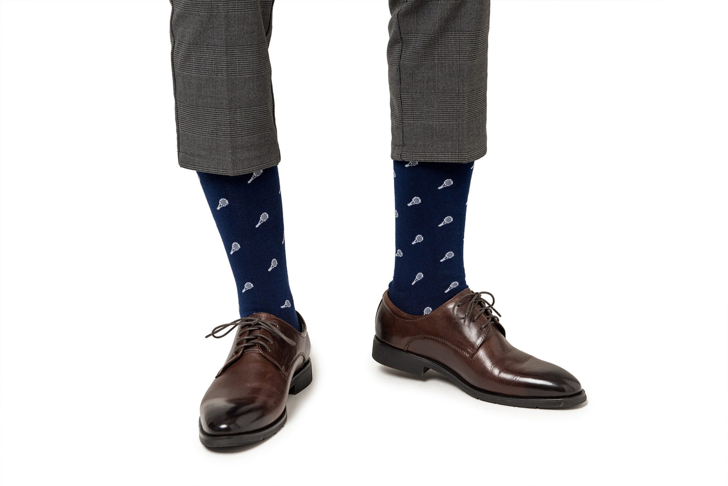 Person wearing gray checkered pants and brown leather shoes with Tennis Socks, blending comfort and performance effortlessly.