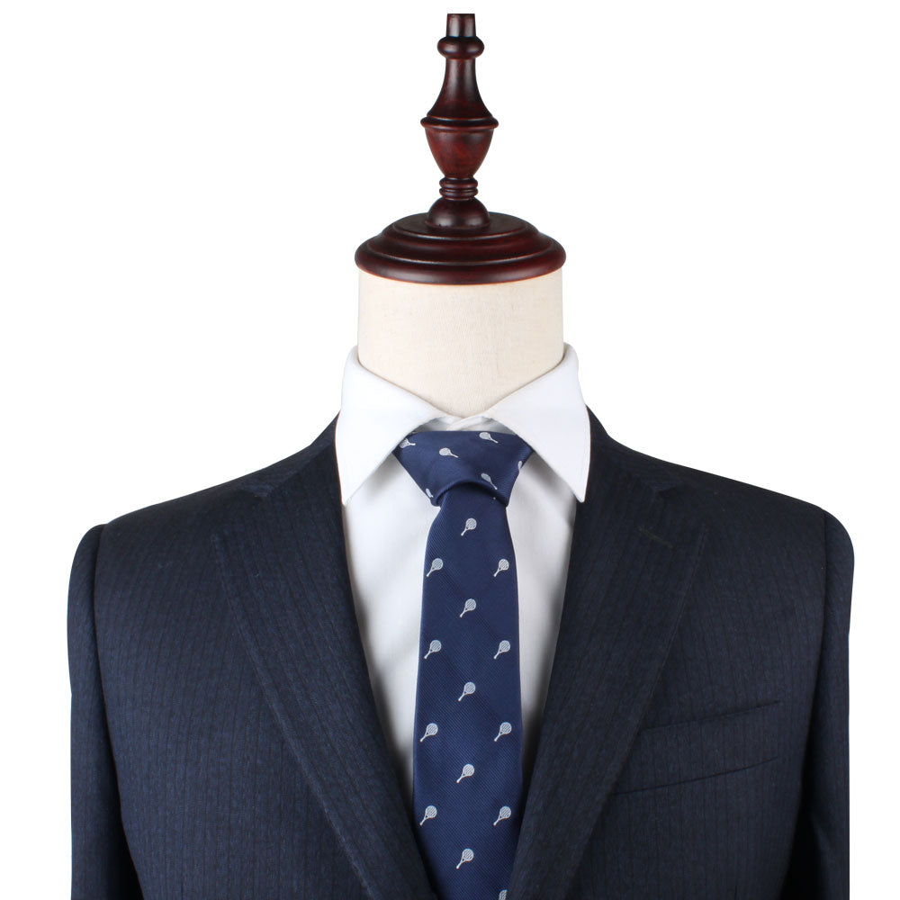 A mannequin dressed in a dark pinstripe suit, white dress shirt, and the Tennis Slim Tie featuring a small repeating pattern exudes timeless refinement.