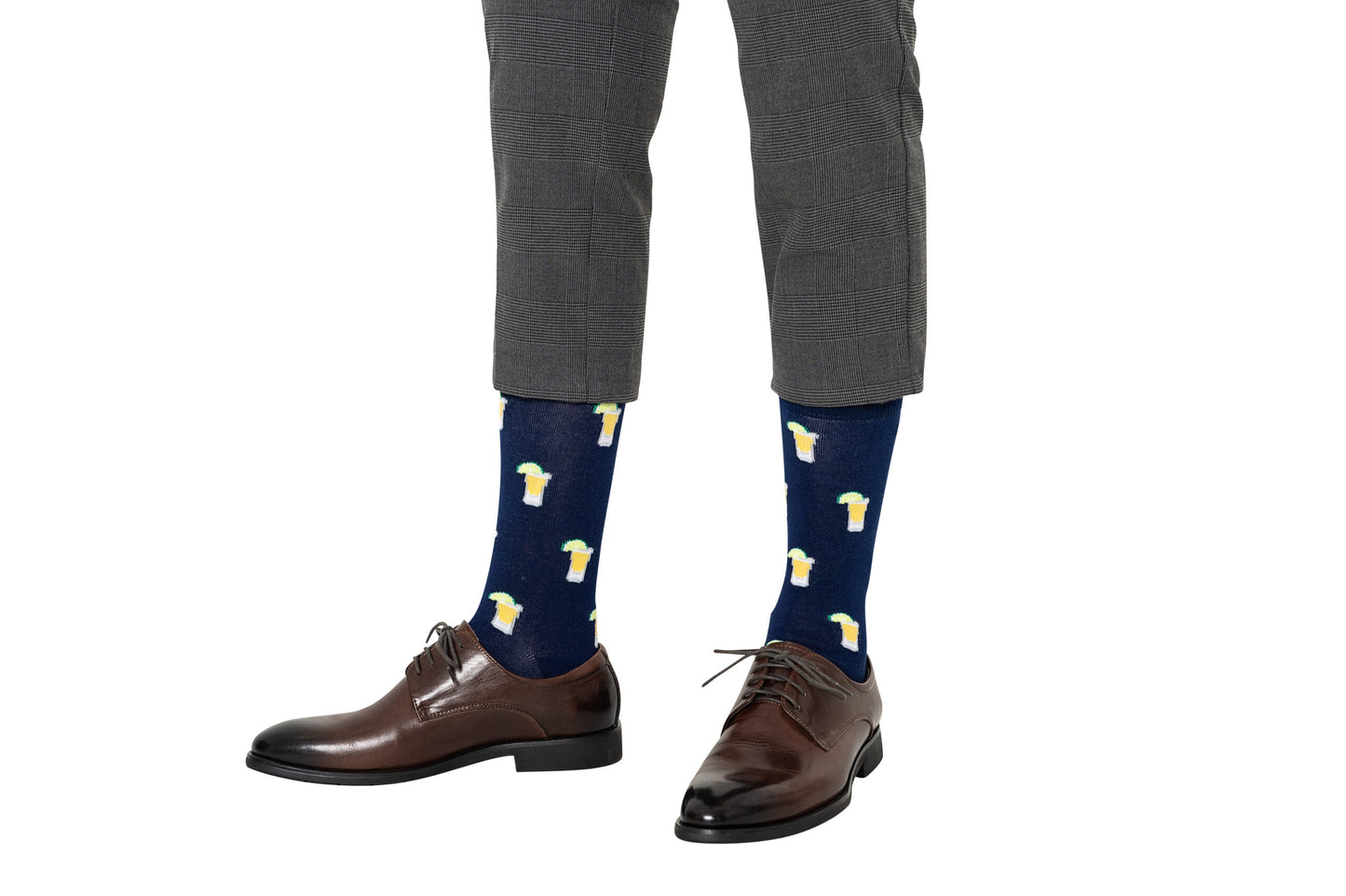 A person wearing gray cropped pants, brown dress shoes, and blue Tequila Socks with a beer mug pattern stands on a white background.