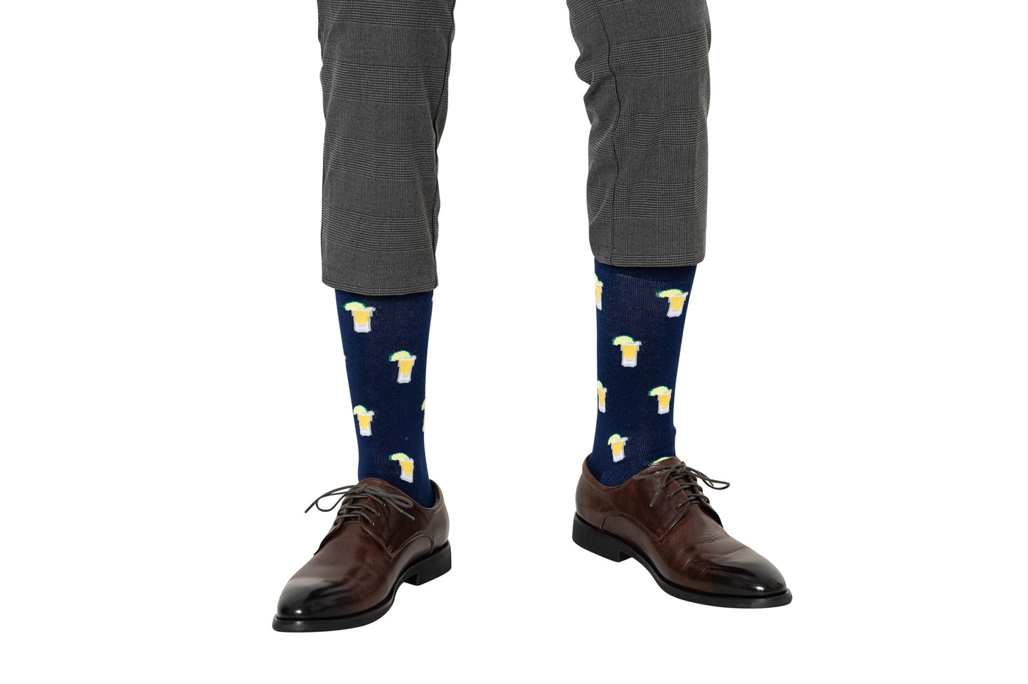 A person wearing gray dress pants, dark brown dress shoes, and Tequila Socksânavy blue socks with beer mug patternsâstands against a white background, perfect for tequila lovers who want fun party socks.