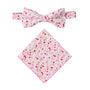 The Tonal Pink Azalea Floral Cotton Bow Tie & Pocket Square Set features a matching white base with pink, red, and green flowers—ideal for weddings. Displayed on a white background.