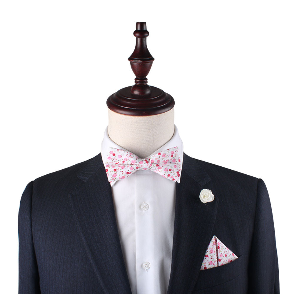 A mannequin wears a dark suit, white shirt, Tonal Pink Azalea Floral Cotton Bow Tie & Pocket Square Set, and a white flower lapel pin—ideal for weddings—posed against a white background.