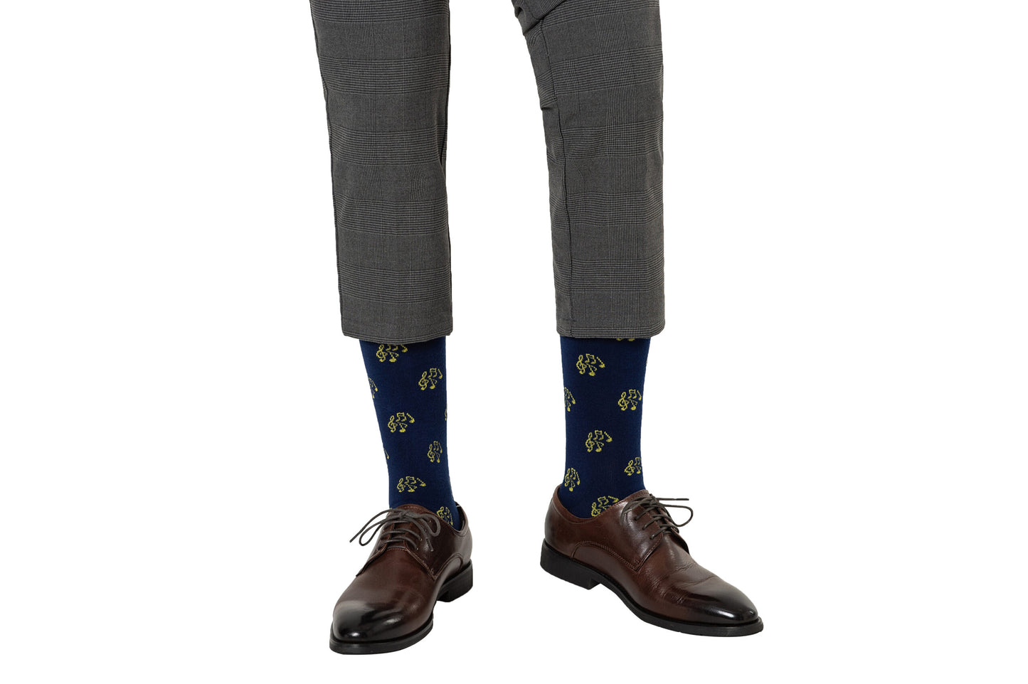 Someone wears gray plaid pants, brown dress shoes, and blue Musical Note Socks featuring a yellow dog pattern—ideal for music lovers or musicians seeking a playful style.