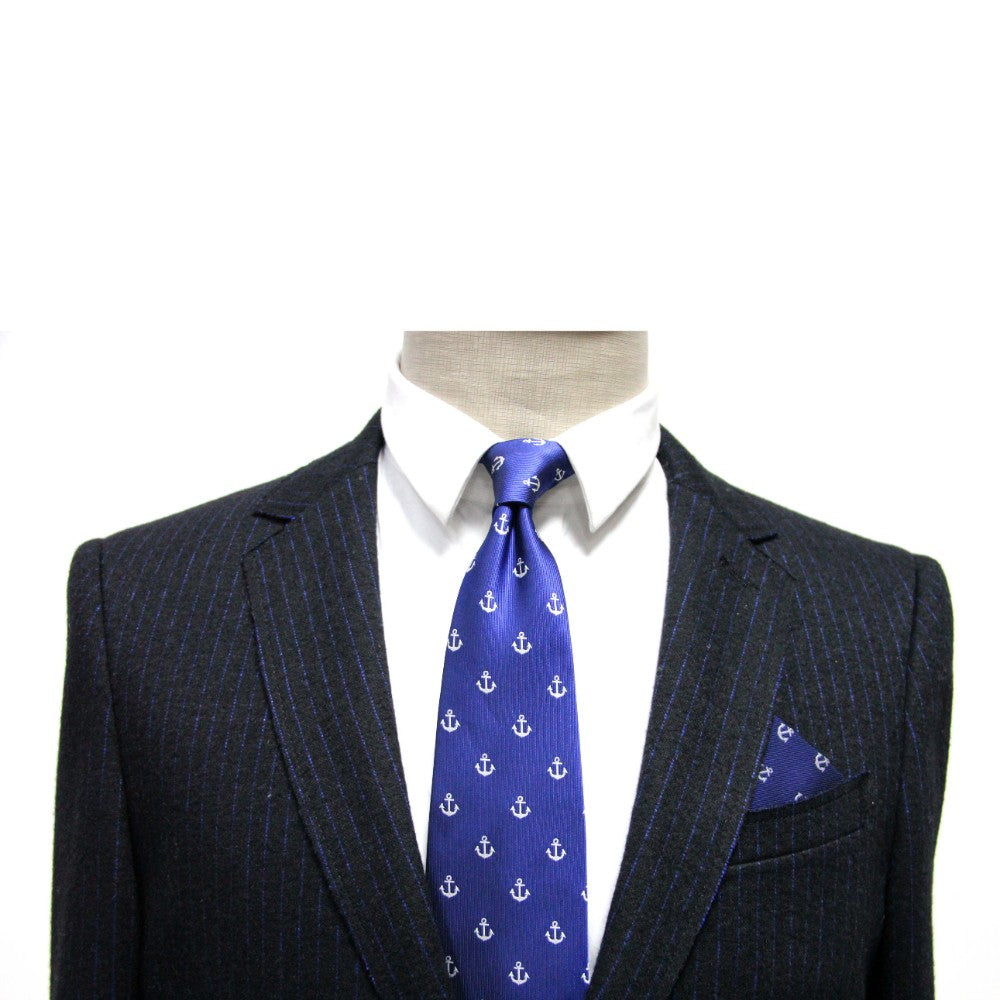 A mannequin exudes nautical charm in a pinstripe suit, complemented by a white shirt and a blue tie adorned with white anchors, finished off with the Navy White Anchor Pocket Square against a crisp navy background.