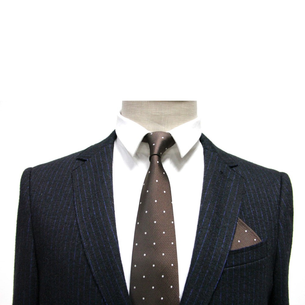 A headless mannequin displays a dark pinstripe suit with a white shirt, complemented by a classic brown polka dot tie. The timeless Brown White Polka Dot Pocket Square, matching the tie, is neatly tucked into the breast pocket of the suit.