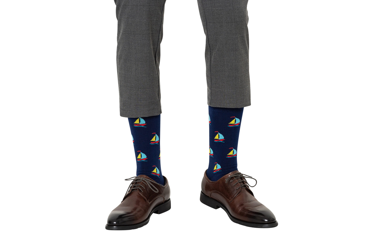 A person wearing gray plaid pants, dark brown dress shoes, and Sail Boat Socks—ideal for ocean lovers seeking a nautical accent to their outfit.