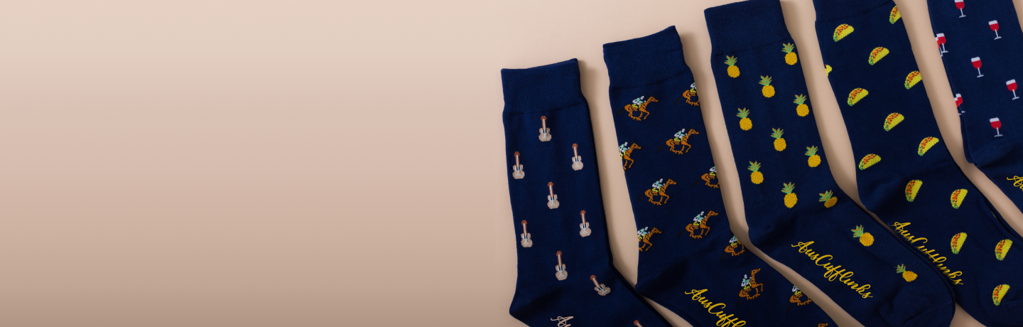A collection of navy blue socks with various colorful patterns spread out in a line on a beige background.